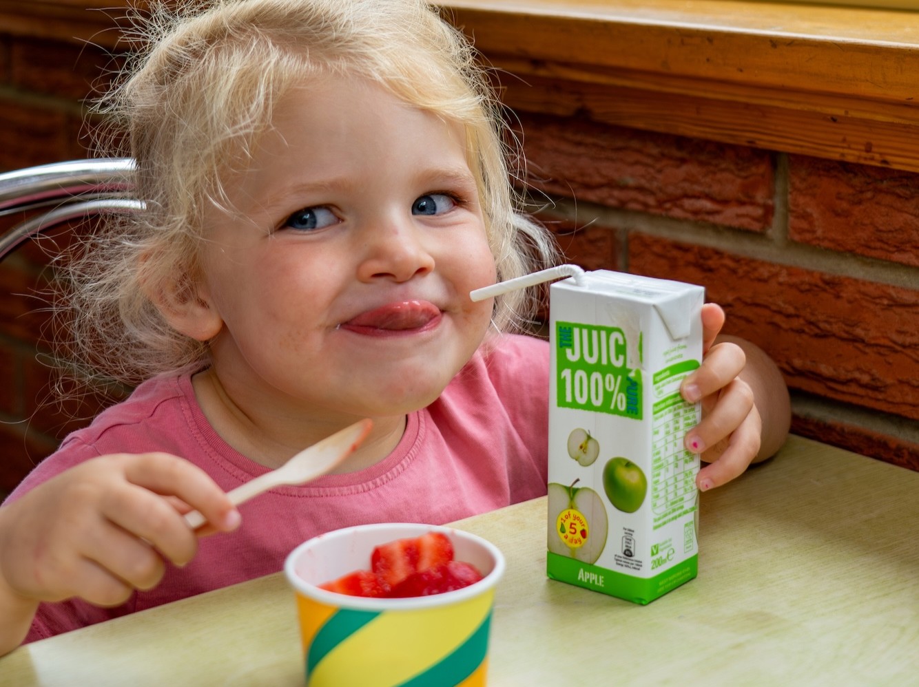 Little Girl Drinking Juice, Eating Strawberries At Whistlestop Cafe