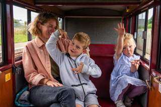 Mum with son and daughter in a carriage travelling the railway